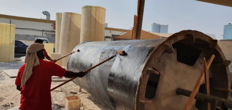 Hand lay-up in progress: a worker rolling out laminate on a large-diameter GRP cylinder